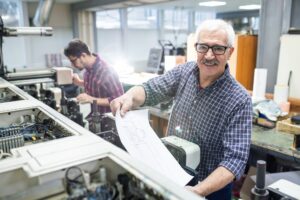 Man getting printed paper out of printing press